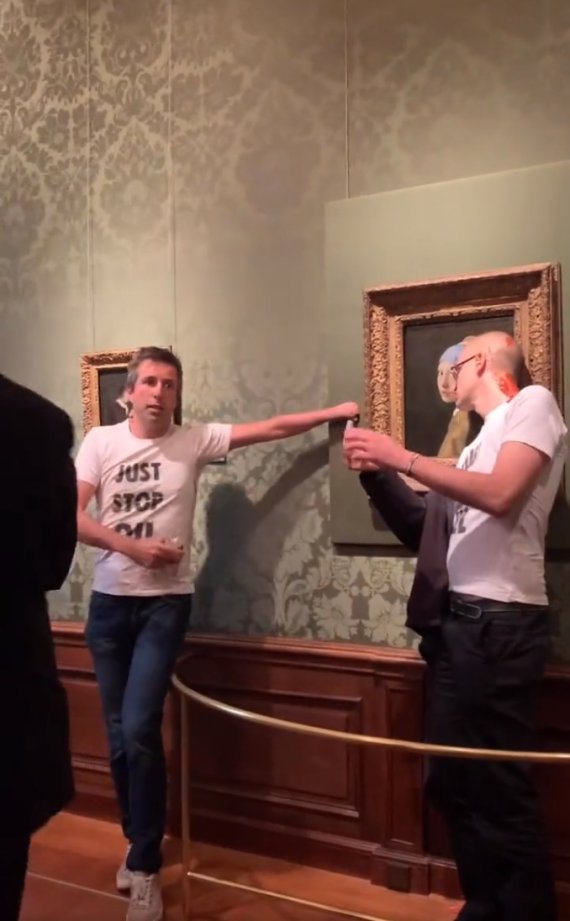 27일(현지시간) 네덜란드 헤이그의 마우리츠하이스 미술관에서 '저스트 스톱 오일(Just Stop Olil)' 활동가들이 요하네스 베르무르의 대표작 '진주귀고리를 한 소녀'를 타깃으로 시위하고 있다. 사진은 트위터 갈무리.