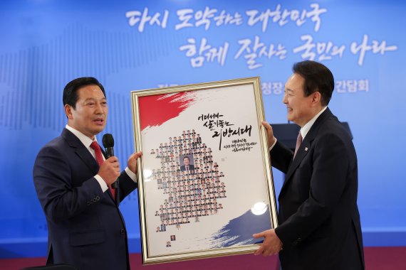 윤석열 대통령이 28일 오후 서울 용산구 전쟁기념관에서 열린 전국 시장·군수·구청장 초청 오찬간담회에서 대한민국시장·군수·구청장협의회 회장인 조재구 대구 남구청장으로부터 대통령과 시장, 군수, 구청장들의 사진을 한반도 모양으로 담은 액자를 선물받고 있다. (대통령실 제공) 2022.10.28/뉴스1 ⓒ News1 안은나 기자