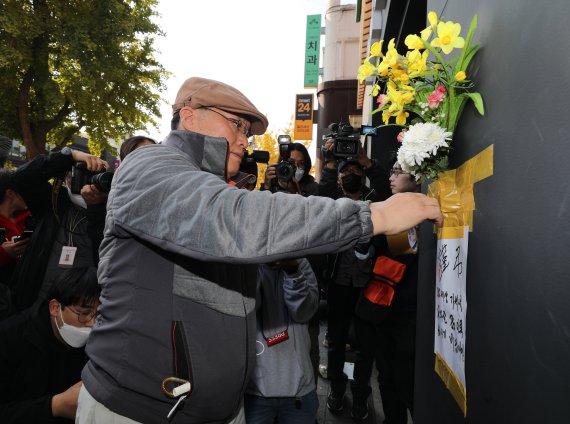 [서울=뉴시스] 김금보 기자 = 30일 오후 서울 용산구 이태원 할로윈 참사 현장 인근 건물 외벽에 한 시민이 근조화를 부착하고 애도하고 있다. 2022.10.25. kgb@newsis.com