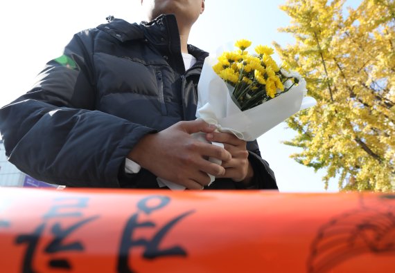 [서울=뉴시스] 김금보 기자 = 30일 오후 서울 용산구 이태원 압사 사고 현장에서 한 시민이 근조화를 들고 추모 공간 마련을 기다리고 있다. 2022.10.30. kgb@newsis.com