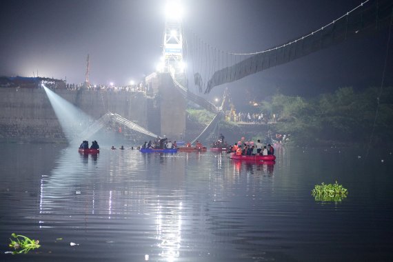 TOPSHOT - Indian rescue personnel conduct search operations after a bridge across the river Machchhu collapsed in Morbi, some 220 kms from Ahmedabad, early on October 31, 2022. - At least 75 people were killed on October 30 in India after an almost 150-year-old colonial-era pedestrian bridge collaps