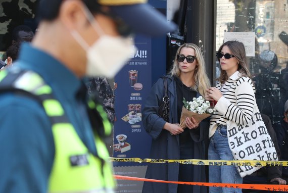30일 오후 서울 용산구 이태원 압사 사고 현장 인근에서 외국인들이 추모를 위해 꽃을 들고 있다. 이태원 압사사고로 발생한 인명피해는 이날 현재 사망 151명, 중상 19명, 경상 63명이다. 2022.10.30/뉴스1 ⓒ News1 임세영 기자