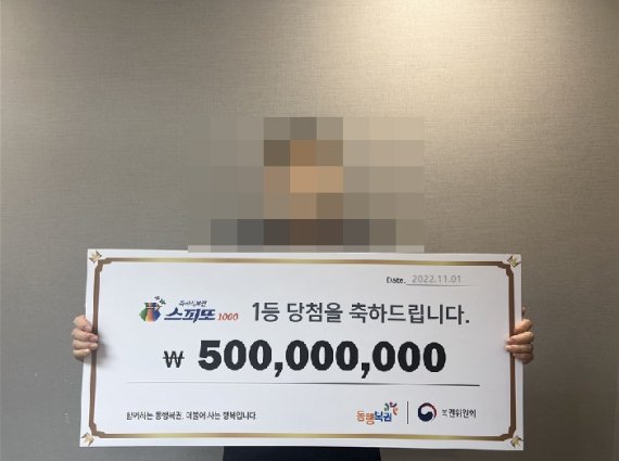 스피또1000 1등 당첨자가 팻말을 들고 당첨을 기념하고 있다. 출처=동행복권