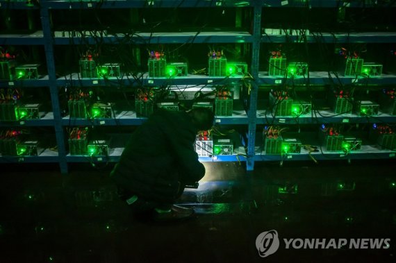 epa06262776 YEARENDER 2017 PHOTO ESSAYS (04/26) Bitcoin miner Huang inspects a malfunctioning mining machine during his night shift at the Bitcoin mine in Sichuan Province, China, 26 September 2016. Miners can check a machine's condition and operations using phones and personal computers. For most i