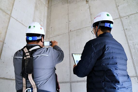 롯데건설 직원들이 현장에서 스마트폰으로 콘크리트 균열을 촬영(좌측)하고 이를 태블릿PC에서 확인(우측)하고 있다. 롯데건설 제공