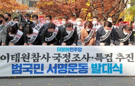 이재명 더불어민주당 대표(오른쪽에서 4번째)를 비롯한 당 지도부들이 지난 11일 서울 여의도역 인근에서 열린 이태원 참사 국정조사·특검 추진 범국민 서명운동 발대식에서 서명을 하고 있다. 뉴스1화상