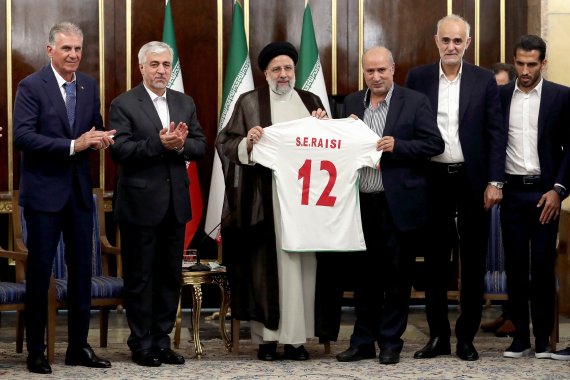 지난 14일(현지시간) 이란 테헤란에서 카타르 월드컵에 출전할 이란 축구 대표팀 선수단이 에브라힘 라이시 대통령을 예방해 팀 유니폼을 선물하고 있다.로이터뉴스1