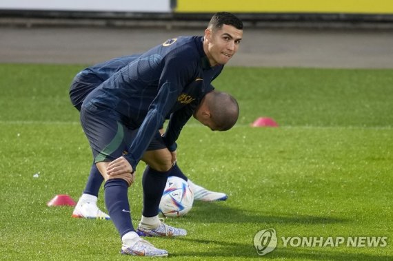 Cristiano Ronaldo stretches with teammate Pepe, in the background, during a Portugal soccer team training session in Oeiras, outside Lisbon, Monday, Nov. 14, 2022. Portugal will play Nigeria Thursday in a friendly match in Lisbon before departing to Qatar on Friday for the World Cup. (AP Photo/Arman