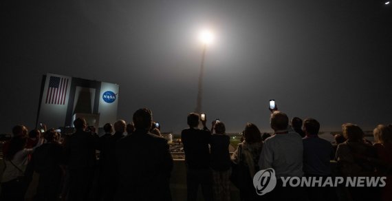 아르테미스I 로켓 발사 장면을 촬영하는 사람들 In this handout photo provided by NASA on November 16, 2022, people watch as the Artemis I unmanned lunar rocket lifts off from launch pad 39B at NASA's Kennedy Space Center in Cape Canaveral, Florida. - NASA's Artemis 1 mission is a 25-and-a-half day voyage beyond the far 