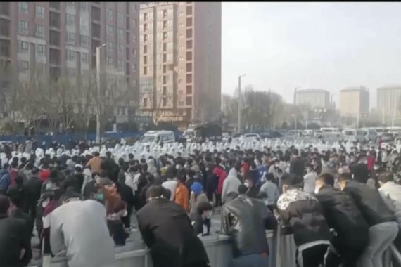 [정저우=AP/뉴시스] 23일 중국 허난성 정저우 폭스콘 공장에서 수백명의 노동자들이 시위를 벌인 가운데 방호복을 입은 보안요원들과 대치하고 있다. 2022.11.24
