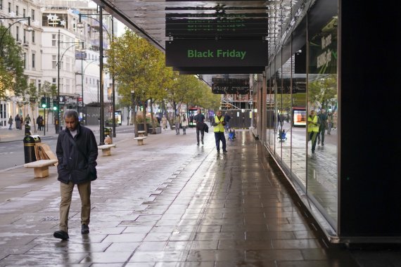 [런던=AP/뉴시스]한 남자가 25일(현지시간)영국 런던 옥스포드 거리의 한 소매점 밖에 있는 '블랙프라이데이' 간판 옆을 지나가고 있다. 2022.11.26