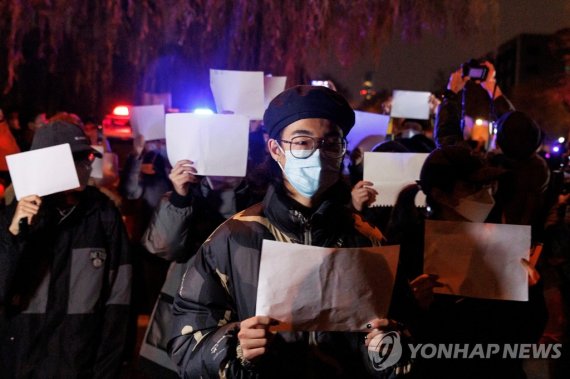 27일 중국 베이징에서 열린 우루무치 화재 희생자 추도식에서 코로나19 봉쇄 조치에 반대하는 시민들이 검열에 대한 저항의 상징으로 '백지 시위'를 펼치고 있다. 사진=로이터연합뉴스