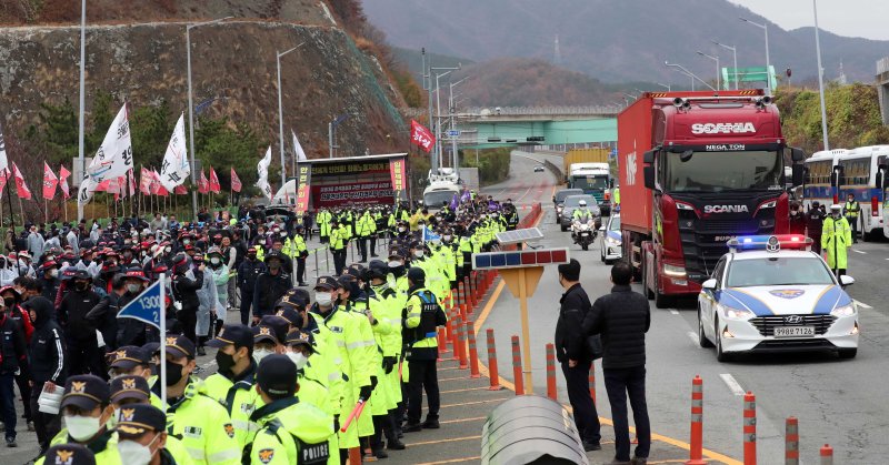 ▲민주노총 공공운수노조 화물연대본부 총파업 엿새째인 11월 29일 부산 강서구 부산신항 교차로에서 화물연대 부산본부 조합원들이 총파업 투쟁 승리 결의대회를 열고 거리행진을 펼치고 있는 가운데 경찰 순찰차 등의 에스코트를 받는 화물차가 이동하고 있다. /사진=뉴시스