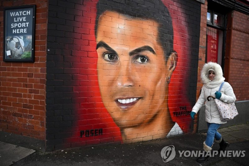 영국 맨체스터에 그려진 호날두 벽화 A pedestrian walks past a mural of Manchester United's Cristiano Ronaldo, near Old Trafford stadium, home ground of Manchester United football team, in Manchester, northern England, on November 23, 2022. - Manchester United's owners said Tuesday they were ready to sell the club a