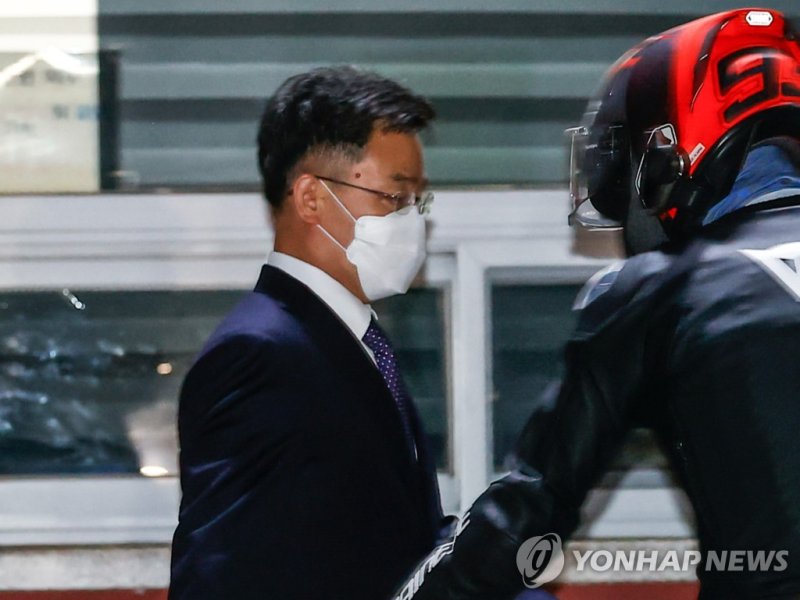 서울구치소 나서는 김만배 씨가 헬멧을 쓴 최우향 씨로부터 도움을 받고 있다. 사진=연합뉴스