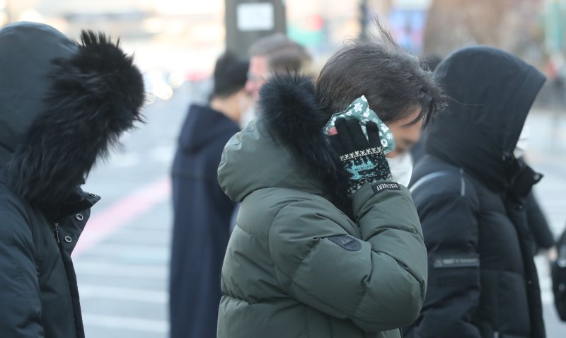 강력한 한파가 찾아온 14일 오전 서울 종로구 광화문네거리에서 직장인이 핫팩을 귀에 대고 출근하고 있다. 뉴시스