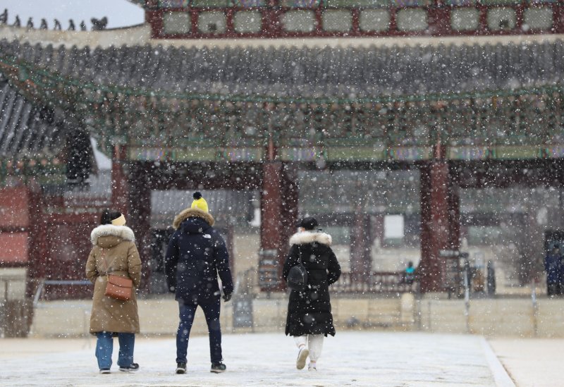 서울을 비롯한 중부 지방에 대설주의보가 내려진 15일 서울 경복궁을 찾은 외국인 관광객들이 내리는 눈을 맞으며 고궁을 거닐고 있다. 2022.12.15/뉴스1 ⓒ News1 신웅수 기자