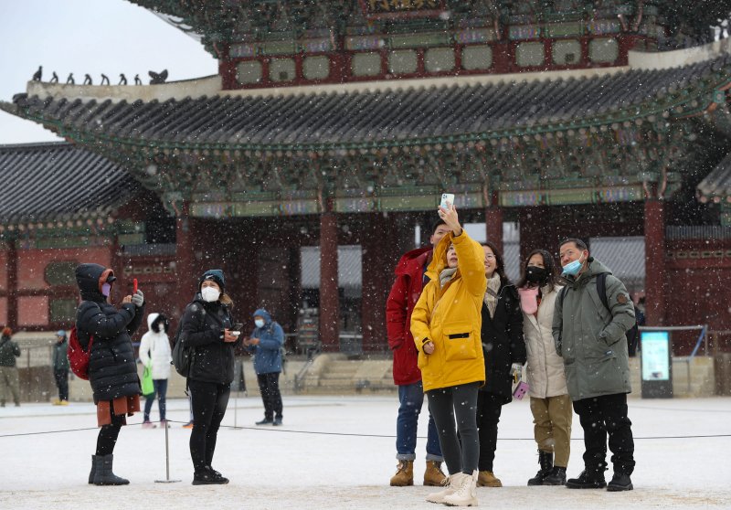 서울을 비롯한 중부 지방에 대설주의보가 내려진 15일 서울 경복궁에서 외국인 관광객들이 내리는 눈을 맞으며 셀카를 찍고 있다. 2022.12.15/뉴스1 ⓒ News1 신웅수 기자