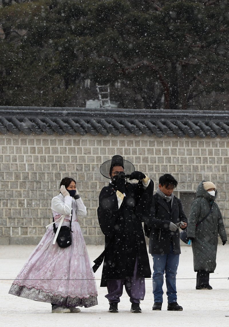 서울을 비롯한 중부 지방에 대설주의보가 내려진 15일 서울 경복궁을 찾은 외국인 관광객들이 내리는 눈을 맞으며 설경을 즐기고 있다. 2022.12.15/뉴스1 ⓒ News1 신웅수 기자