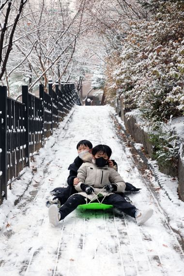 눈썰매 타며 함박 웃음짓는 어린이들