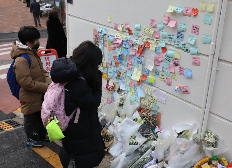 지난 13일 서울 강남구 언북초등하교 앞에 마련된 어린이보호구역(스쿨존)에서 음주운전 차량에 치어 숨진 초등학생을 기리는 추모 공간에서 학생들이 기도를 하고 있다. 뉴스1