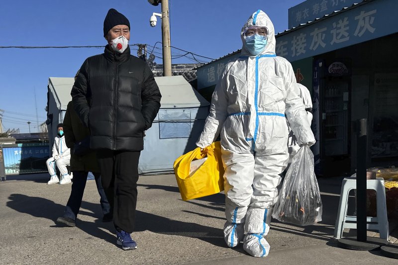 지난 17일 중국 베이징의 한 화장장에서 코로나19로 가족을 잃은 시민이 보호복을 입은채 인계받은 유품을 가지고 걸어나오고 있다. AP연합뉴스