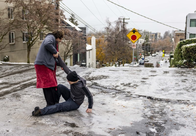한 남성이 빙판길에 넘어진 친구가 일어나는 것을 돕고 있다. (자료사진) 뉴시스