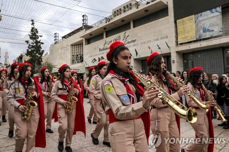 베들레헴 예수탄생 교회 앞 구유 광장을 지나는 성탄 전야 축하 행렬. Members of the scouting movement march during Christmas eve celebrations at the Manger Square outside the Church of the Nativity in the biblical city of Bethlehem in the occupied West Bank on Christmas eve on December 24, 2022. (Photo by HAZEM BADER / AFP)