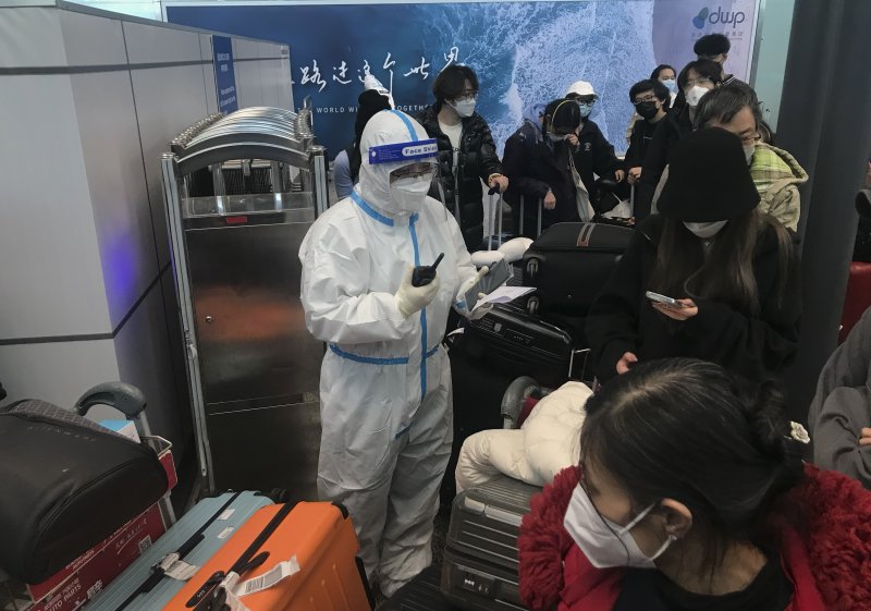 지난 25일 중국 광둥성 광저우의 바이윈 공항에서 보건 당국 직원이 격리를 위해 이동하는 입국자들을 감독하고 있다.AP연합뉴스