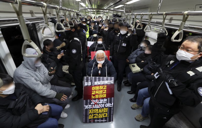 전국장애인차별철폐연대(전장연) 박경석 대표(가운데)가 지난 20일 오전 서울 광화문역에서 지하철에 탑승해 장애인 권리예산 보장을 촉구하는 선전전을 벌이고 있다. 전장연의 출근길 지하철 시위는 내년 1월 2일 다시 시작된다. 뉴시스
