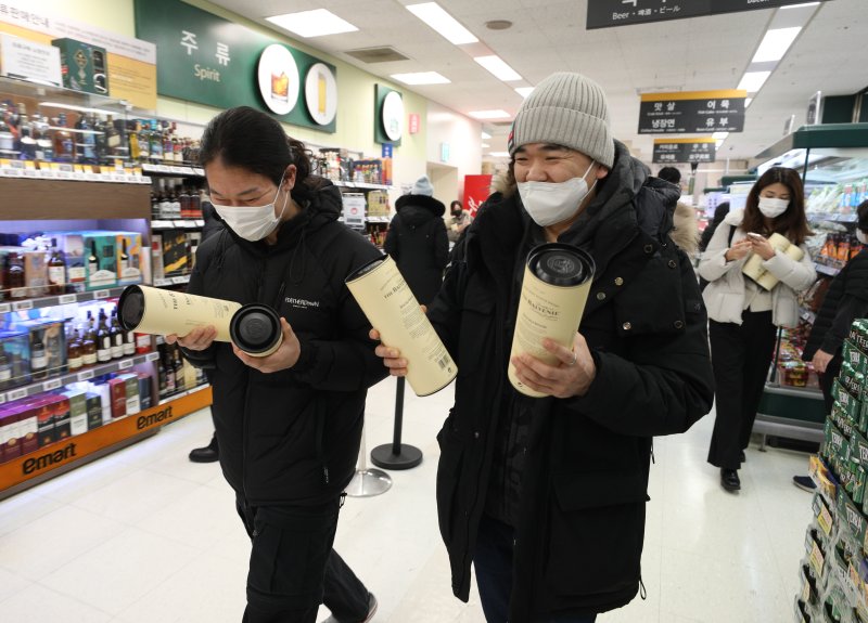 6일 서울 이마트 용산점에서 시민들이 한정판 위스키를 구매한 후 미소 짓고 있다. 이마트는 오는 7일까지 발베니, 맥켈란을 비롯해 2022년 인기 위스키 7종 할인 행사를 진행한다. 2023.1.6/뉴스1 ⓒ News1 신웅수 기자