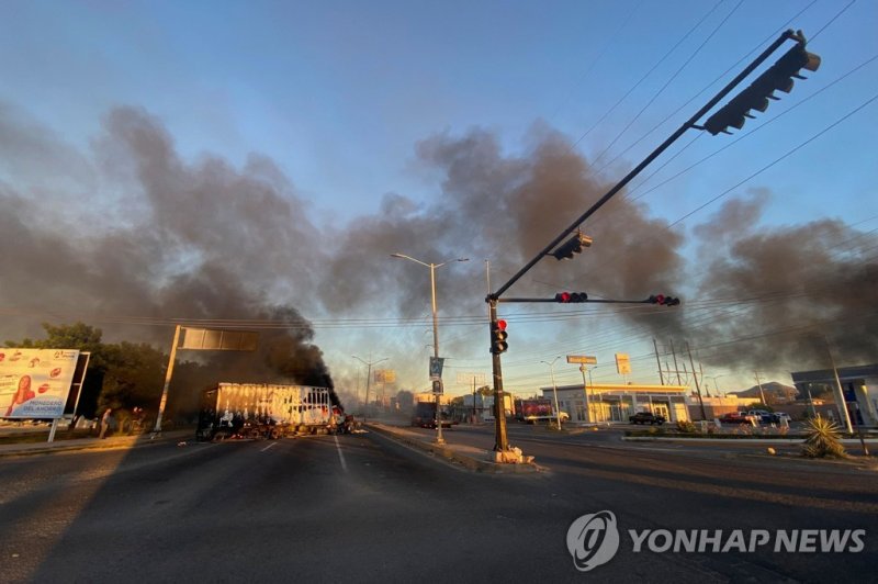 검은 연기 뒤덮은 멕시코 쿨리아칸 시내 Burning vehicles are seen crossed in the street during an operation to arrest the son of Joaquin "El Chapo" Guzman", Ovidio Guzman, in Culiacan, Sinaloa state, Mexico, on January 5, 2023. (Photo by Marcos Vizcarra / AFP)