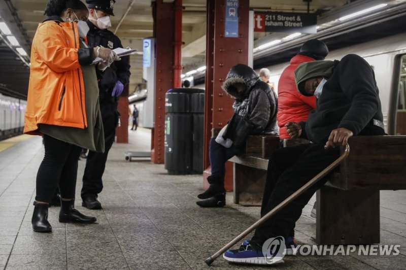 미국 뉴욕 지하철역에서 잠을 자는 노숙자 앞에 선 경찰관 FILE - A homeless outreach worker and New York police officer assist passengers found sleeping on subway cars at the 207th Street A-train station, Thursday, April 30, 2020, in the Manhattan borough of New York. In New York City's latest effort to address a mental heal