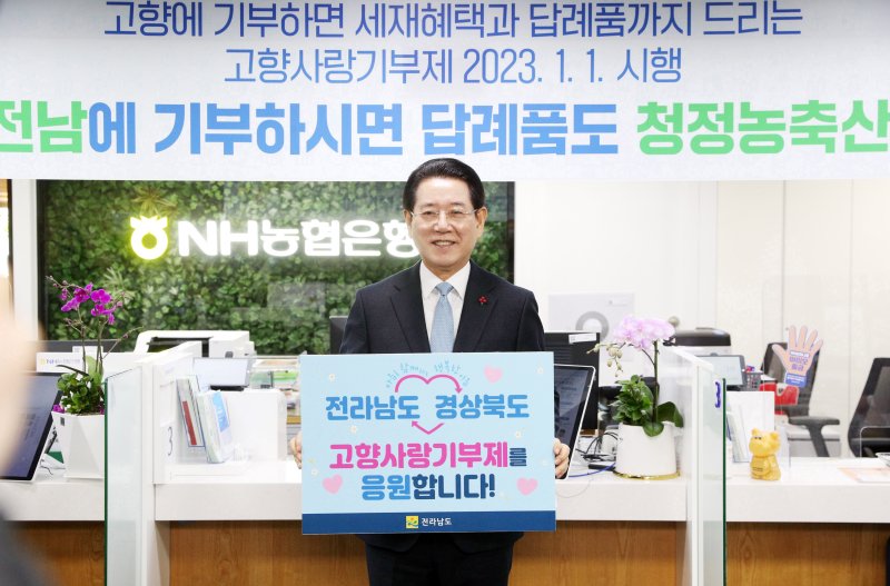 [무안=뉴시스] 이창우 기자=김영록 전남도지사가 10일 오전 NH농협은행 전남도청 지점에서 경북도에 기부금을 기탁한 후 전남과 경북 양 지역의 고향사랑기부제를 응원하는 피켓을 들고 기념촬영을 하고 있다. (사진=전남도 제공) 2022.01.10. photo@newsis.com *재판매 및 DB 금지