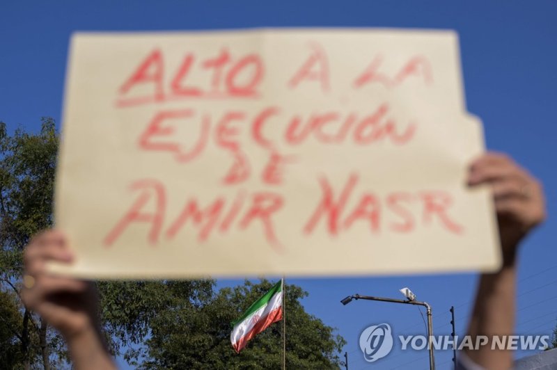 이란인 축구 선수 석방 촉구하는 손팻말 A man holds a sign during a protest against the execution of Iranian footballer Amir Nasr-Azadani -sentenced to death within protests following the death of Mahsa Amini- in front of the Iranian embassy in Mexico City on December 19, 2022. - Amir Nasr-Azadani was arrested in the