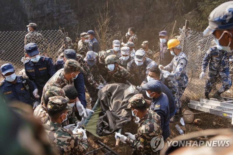 Rescue workers recover the body of a victim of a passenger plane that crashed in Pokhara, Nepal, Sunday, Jan. 15, 2023. A plane making a 27-minute flight to a Nepal tourist town crashed into a gorge Sunday while attempting to land at a newly opened airport, killing at least 68 of the 72 people aboar