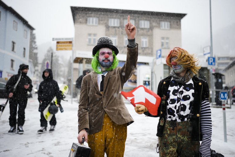 15일(현지시간) 스위스 다보스에서 열리는 세계경제포럼(WEF·다보스포럼) 연차총회를 하루 앞두고 광대 분장을 한 두 남성이 다보스 포럼 반대 시위를 하고 있다. AP뉴시스