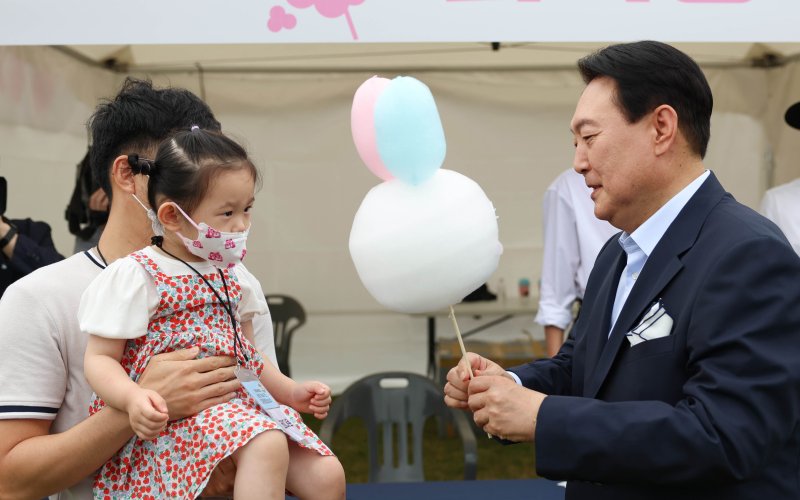 윤석열 대통령이 지난해 6월19일 서울 용산 대통령실 청사 앞 잔디광장에서 열린 '대통령실 이전 기념 주민 초대 행사'에서 지역 소상공인들이 참여한 부스를 찾아 어린이에게 솜사탕을 건네주고 있다. (대통령실 제공) 2022.6.19/뉴스1 ⓒ News1 오대일 기자