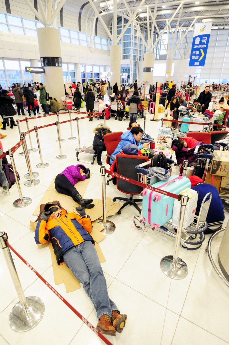 제주지역에 많은 눈이 내려 제주공항이 전편 결항된 가운데 24일 제주국제공항 대합실에 승객들이 종이상자를 펴고 잠을 자고 있다.2016.1.24/뉴스1 ⓒ News1 이석형 기자