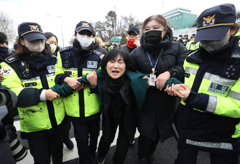 [서울=뉴시스] 김진아 기자 = 10.29 이태원 참사로 숨진 故 이지한 씨의 어머니 조미은 씨와 아버지 이종철 씨가 31일 서울 용산구 대통령 집무실 앞에서 면담 등을 요구하며 진입을 시도하다 제지당하고 있다. 2023.01.31. bluesda@newsis.com