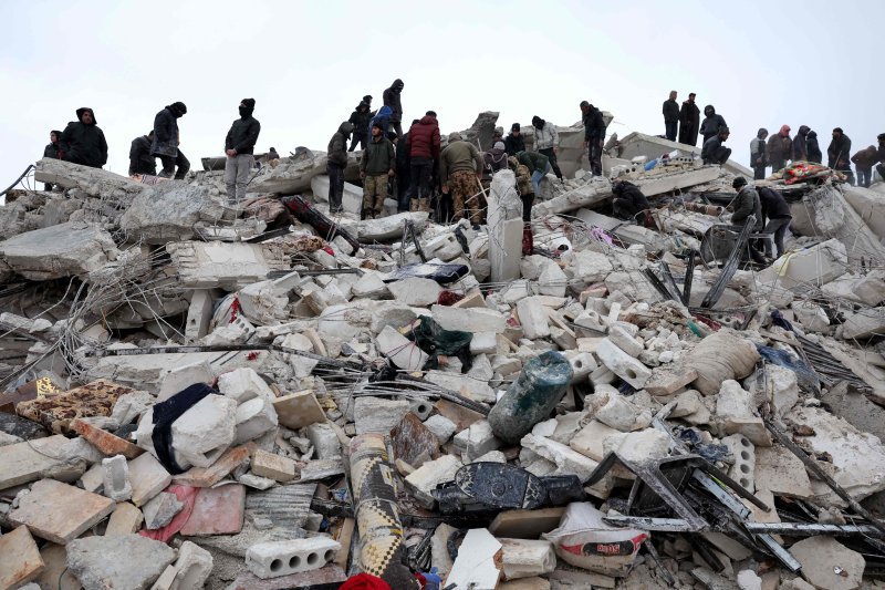 TOPSHOT - Residents and rescuers search for victims and survivors amidst the rubble of collapsed buildings following an earthquake in the village of Besnaya in Syria's rebel-held northwestern Idlib province on the border with Turkey, on February 6, 2022. - At least 1,293 people were killed and 3,411