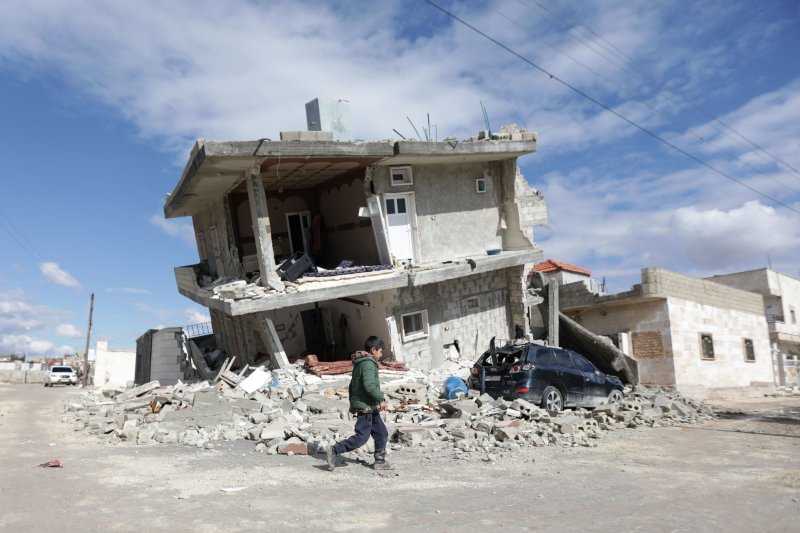 TOPSHOT - A Syrian youth walks past a half collapsed house in the town of Azaz on the border with Turkey on February 7, 2023, following a deadly earthquake. - The Syrian Red Crescent appealed to Western countries to lift sanctions and provide aid after a powerful earthquake has killed more than 1,60