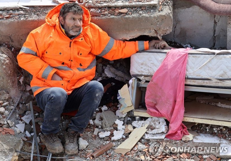 TOPSHOT - Mesut Hancer holds the hand of his 15-year-old daughter Irmak, who died in the earthquake in Kahramanmaras, close to the quake's epicentre, the day after a 7.8-magnitude earthquake struck the country's southeast, on February 7, 2023. - Rescuers in Turkey and Syria braved frigid weather, af