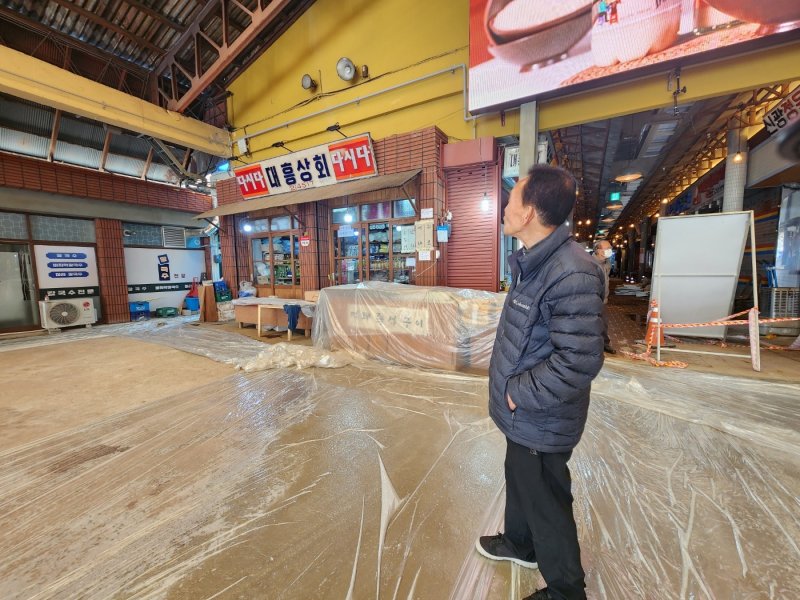 11일 백종원 예산시장 활성화 프로젝트가 중단된 가운데 점포를 운영하는 김지준(77) 씨가 평탄화 작업을 하고 있는 방문객 식사장소를 설명해주고 있다.