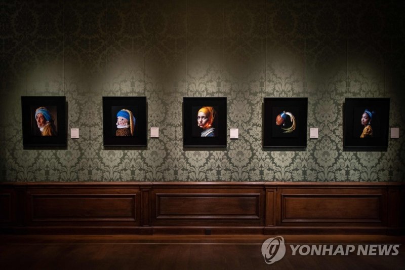마우리츠하위스 미술관이 선정한 5개 작품. 판디컨의 AI 작품이 가운데에 놓여있다. This photograph taken in The Hague on March 9, 2023 shows an image (C) designed with artificial intelligence by Berlin-based digital creator Julian van Dieken (C) and inspired by Johannes Vermeer's painting "Girl with a Pearl Earring" at the Mauritshuis