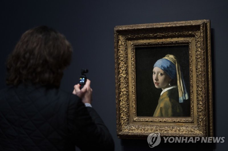 암스테르담 국립미술관에 대여 전시 중인 '진주 귀고리를 한 소녀' 원본 A journalist takes images of Girl with a Pearl Earring during a press preview of the Vermeer exhibit at Amsterdam's Rijksmuseum, Monday, Feb. 6, 2023, which unveils its blockbuster exhibition of 28 paintings by 17th-century Dutch master Johannes Vermeer drawn 