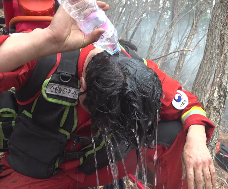 경북 울진군 응봉산 주불을 잡기 위해 헬기 급속로프로 정상에서 투입된 산림청 산림항공본부 공중진화대원들이 진화작업 중 지친 몸을 잠시나마 씻어내고 있다. (산림청제공)2022.3.13/뉴스1 ⓒ News1 최창호 기자