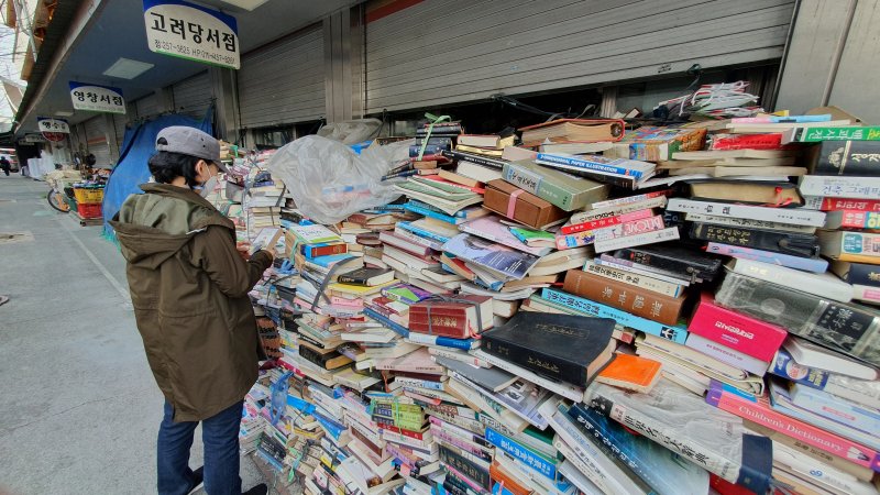 3. 대전 중앙시장 중앙메가프라자 구역에 있는 헌책방에서 한 행인이 가게 앞에 쌓인 책들을 살펴보고 있다. 사진=김원준 기자