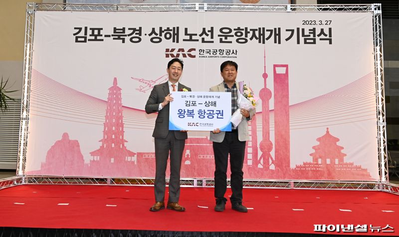 윤형중 한국공항공사 사장(왼쪽)이 27일 김포공항 국제선 터미널에서 김포-상하이 노선을 이용하는 승객에게 운항재개 기념 왕복 항공권을 전달한뒤 기념촬영을 하고 있다. 한국공항공사 제공