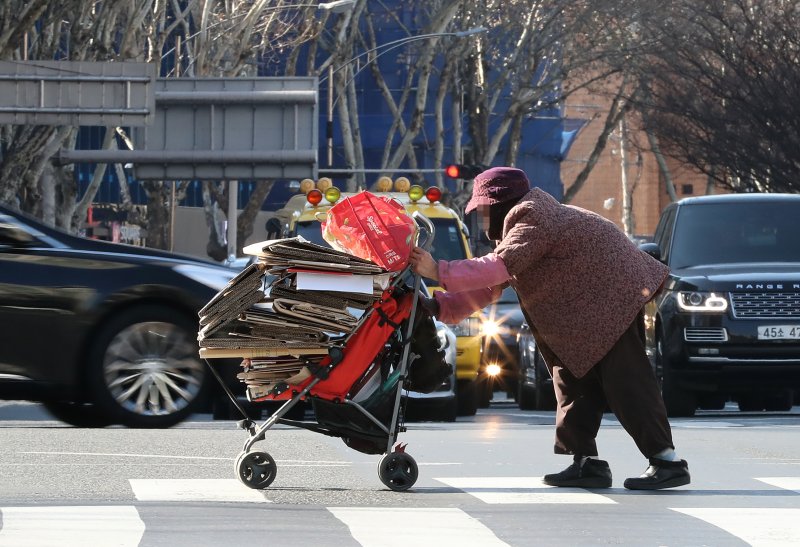 한 노인이 파지가 가득 담긴 수레를 밀며 횡단보도를 건너고 있다. 지자체마다 노인 일자리 문제해결에 고심하고 있지만 현실적인 해법이 없어 노인들의 어려움은 늘고 있다. 뉴스1 ⓒ News1 공정식 기자